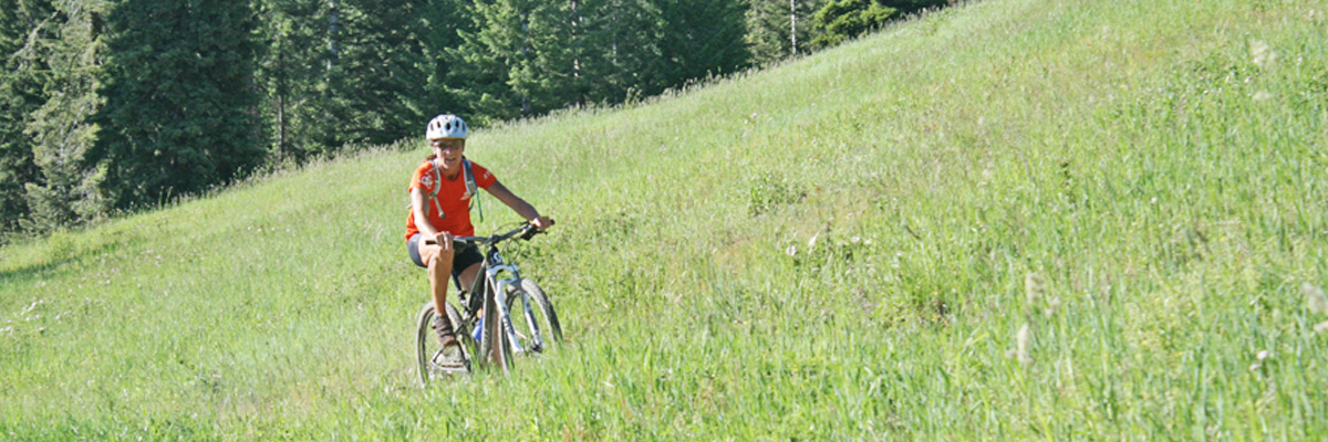 Woman rides mountain bike through tall grass