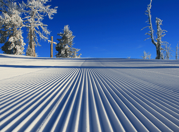 groomed slope under blue sky