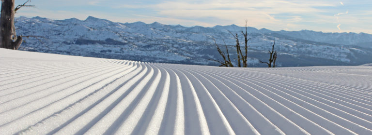 groomed snow with mountains in background
