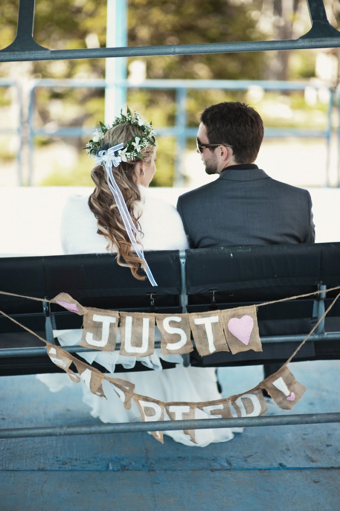 Bride and groom ride chairlift with 'just married' sign