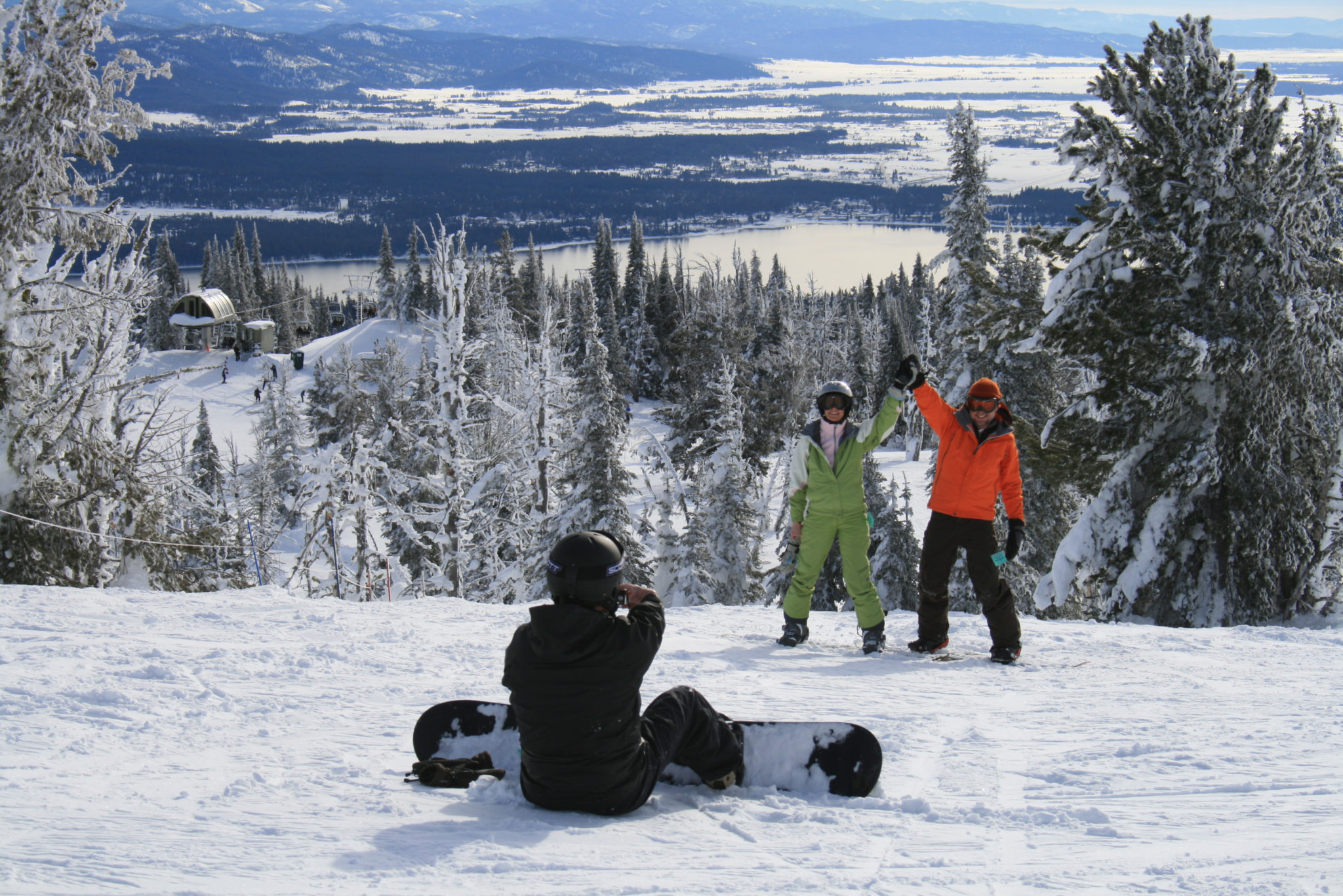 Snowboarder photographs friends at summit.