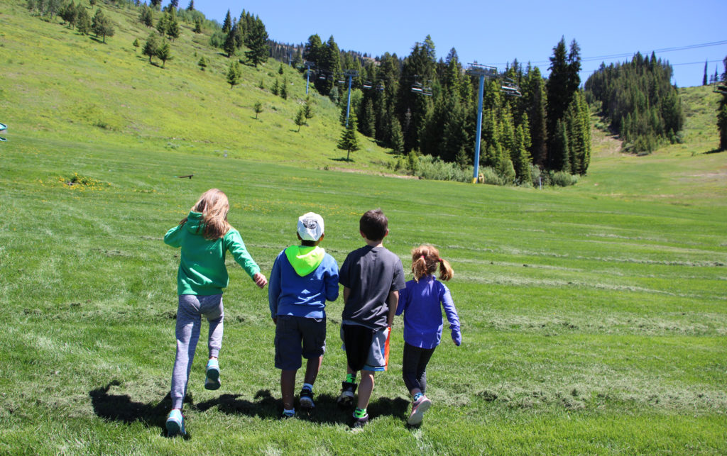 four kids skip on grass
