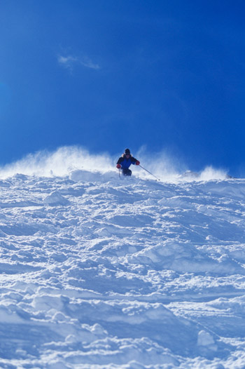 Skier and skiers carving turns down Brundage Mountain snow slopes with ski tips and control, people experiencing the terrain runs at speed during snowboarding season with balance and way to navigate the slope using skis for winter sport menu