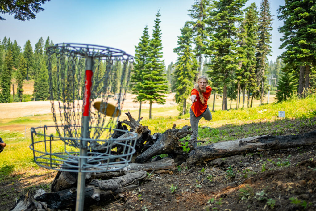 Man puts a disc into the basket on the East Street 9 Disc Golf course. 